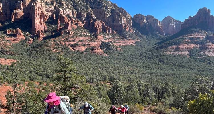 Wanderer, die einen Pfad mit malerischen Ausblicken auf rote Felsen hinaufsteigen.