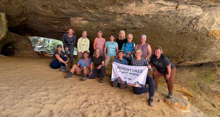 Groupe de personnes posant avec une bannière à l'intérieur d'une formation rocheuse.