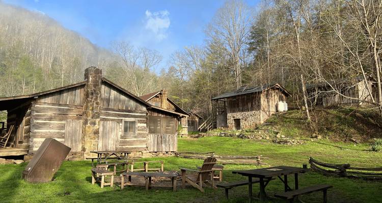 Cabanes en bois rustiques dans une région montagneuse avec de la fumée s'élevant d'une cheminée.
