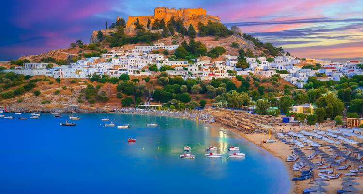 Bright evening view of Lindos with beach and boats.