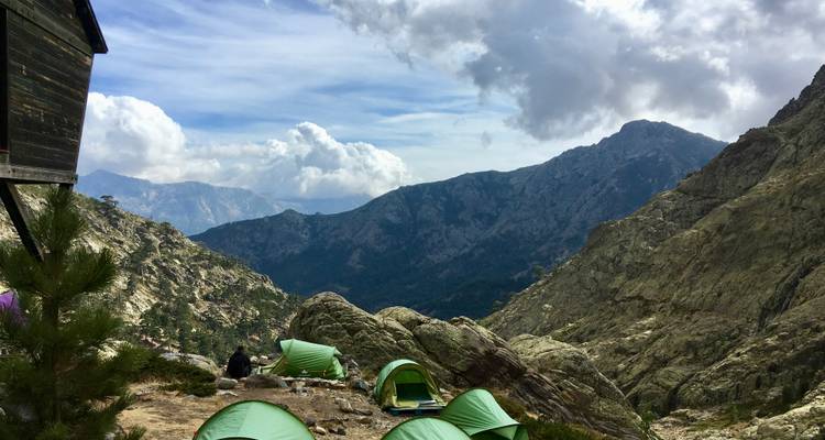 Site de camping avec plusieurs tentes installées dans un paysage montagneux.
