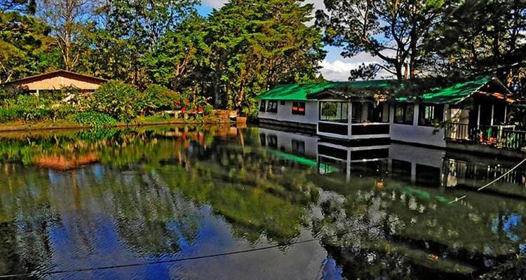 Building by a lake with forest surrounding the scene.