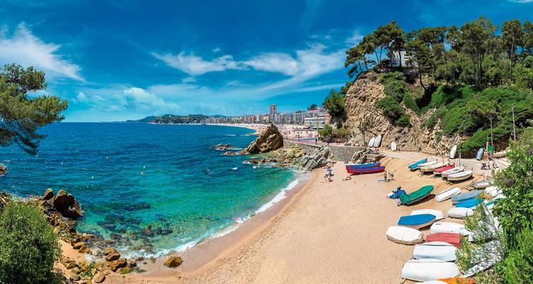 Malerischer Strand mit klarem blauem Wasser und entfernter Stadt.