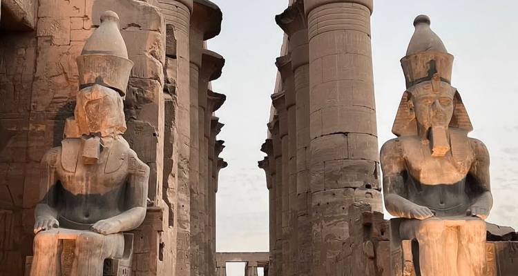 Deux grandes statues de pharaon assis sur un site égyptien antique.