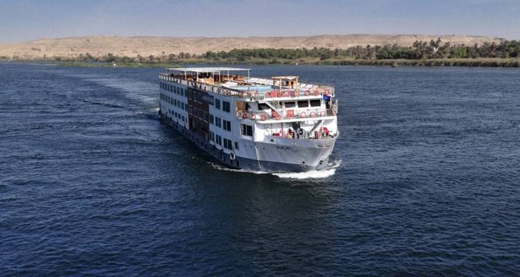Navire de croisière naviguant sur une large rivière sous un ciel dégagé.