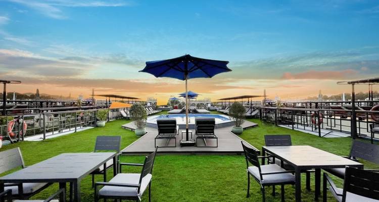 Terrasse avec chaises et parasol au coucher du soleil avec vue sur la rivière.