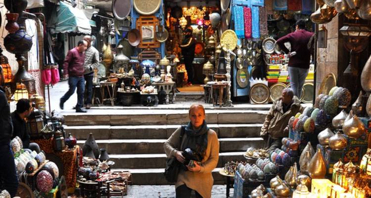 Scène de marché avec boutiques, lanternes et gens qui flânent.