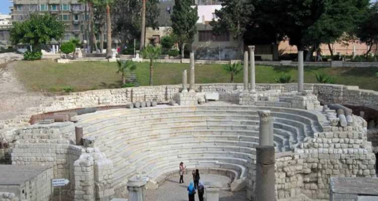 Ruines de théâtre romain avec colonnes et arbres en arrière-plan.
