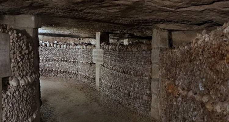 Catacombes souterraines avec des murs en pierre et des arches.