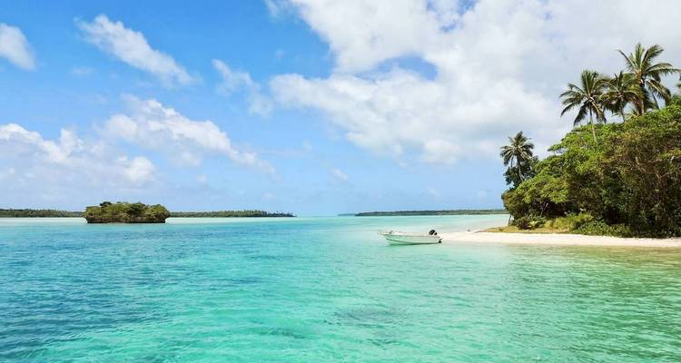 Tropical beach with clear water and a small boat.
