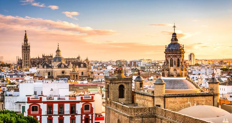 Gouden uur skyline van Sevilla met kathedraalspitsen en warme historische daken.