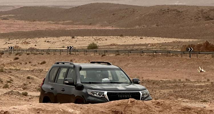 Un véhicule Toyota partiellement submergé dans un terrain sablonneux.
