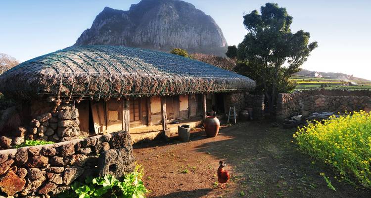 Casa tradicional de piedra con un telón de fondo montañoso en una zona rural de Corea del Sur.