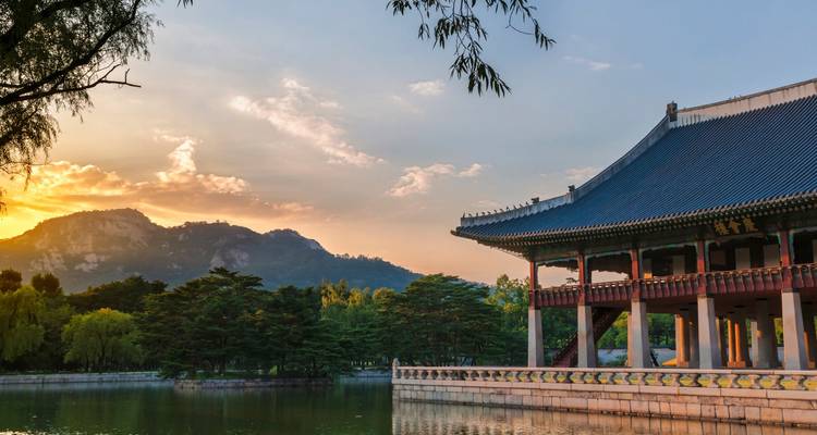 Arquitectura tradicional coreana reflejada en un tranquilo estanque al atardecer.