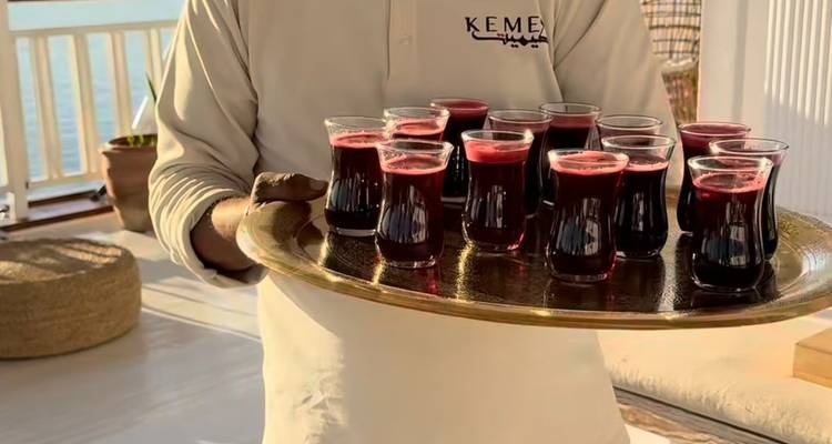 Serveur tenant un plateau de boissons dans des verres traditionnels.