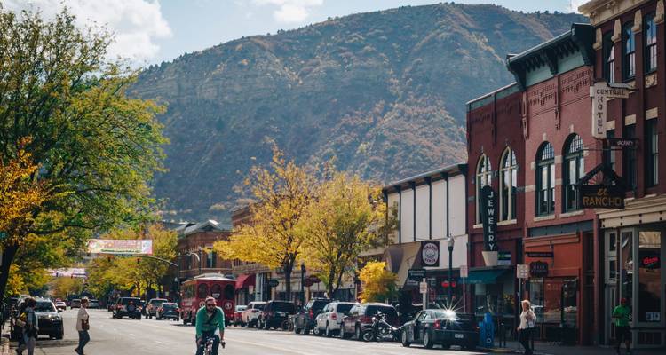 Vue de rue avec boutiques et feuillage d'automne, avec des montagnes en arrière-plan.