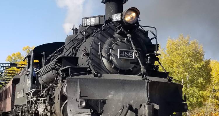 Train à vapeur classique avec feuillage d'automne en arrière-plan.