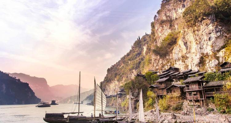 Las casas tradicionales sobre pilotes se aferran a los acantilados de piedra caliza sobre el río Yangtsé al atardecer