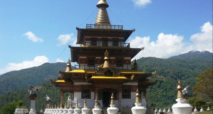 Temple bouddhiste avec des ornements dorés et des stupas autour.