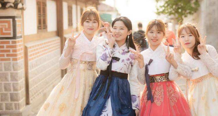 Quatre personnes vêtues de tenues coréennes traditionnelles posant pour une photo.