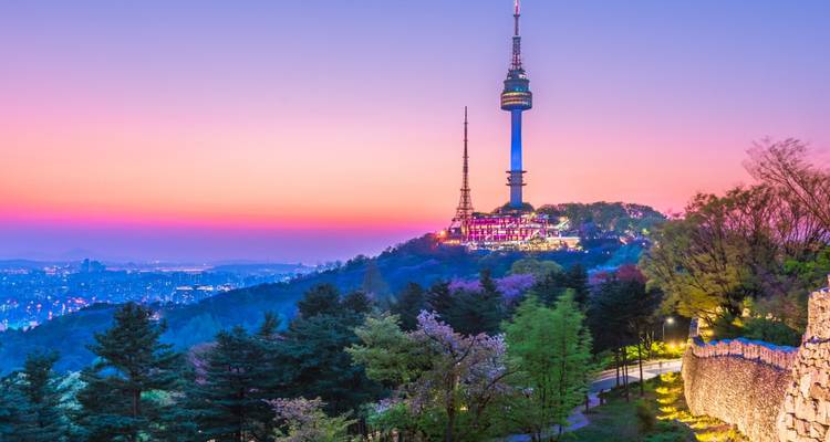 Une tour sur une colline au coucher du soleil avec vue sur la ville.