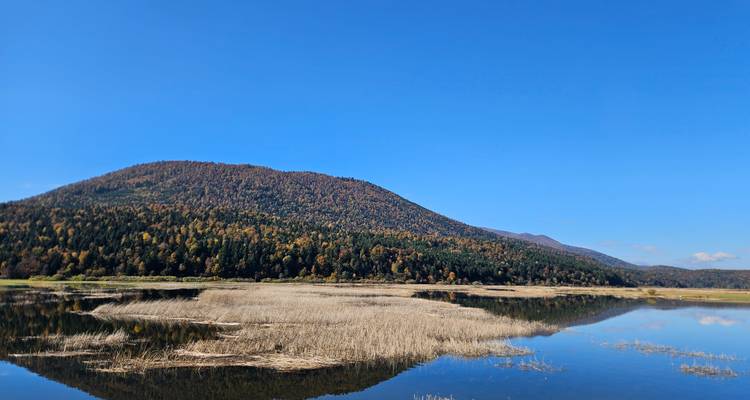 Reflective lake with lush rolling hills in the distance.