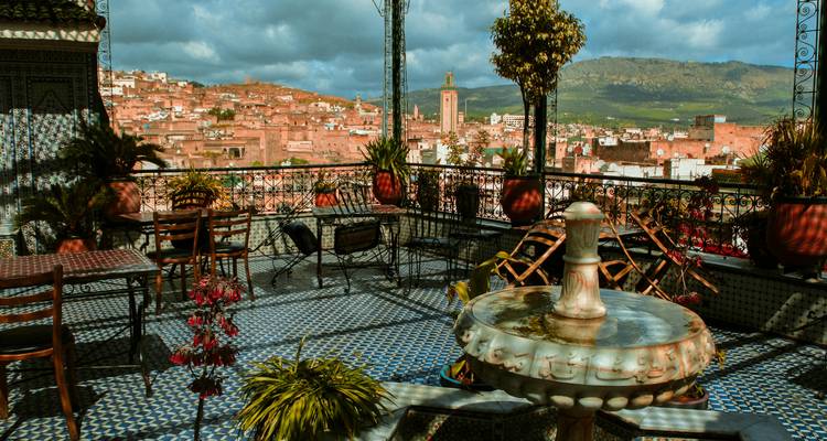 Terrasse avec tables donnant sur une ville marocaine.