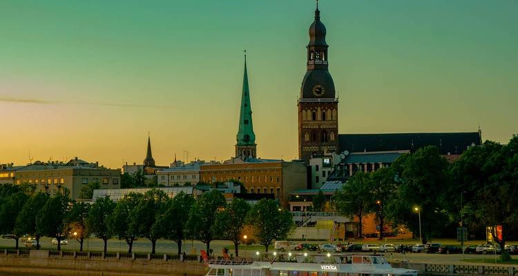 Paysage urbain avec des monuments et un pont au-dessus d'eaux calmes le soir.