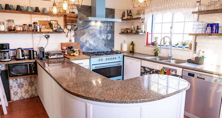 Cuisine moderne avec divers appareils électroménagers, étagères ouvertes et un grand plan de travail.