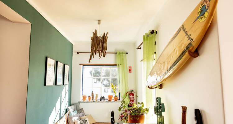 Mur décoré, plafonnier en bois, et une planche de surf accrochée au mur.