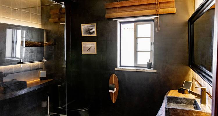 Salle de bain moderne avec un thème noir, lavabo et fenêtre.