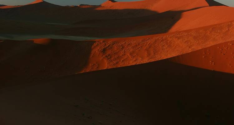 Vue aérienne de dunes de sable rouge projetant de longues ombres.