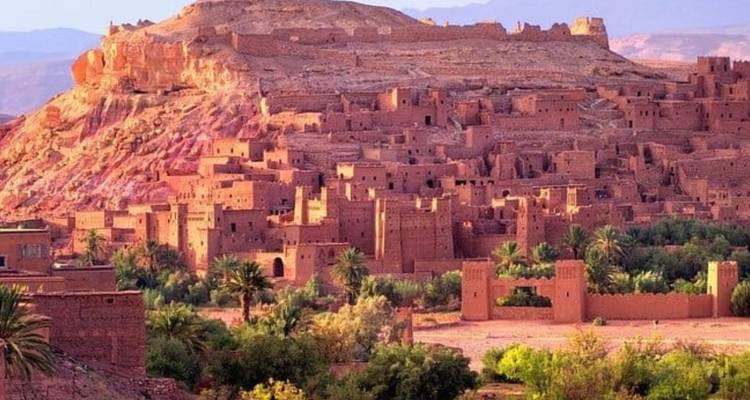 Vue du village d'Aït-Ben-Haddou avec une colline rocheuse en arrière-plan.
