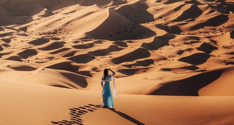 Personne en robe bleue dans un vaste paysage désertique.