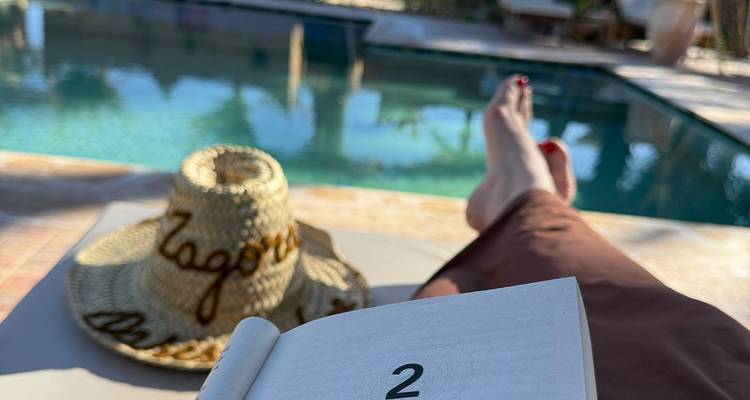 Scène relaxante au bord de la piscine avec un chapeau and un livre.
