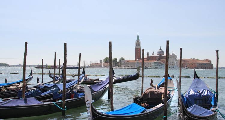 Rangée de gondoles avec église et tour en arrière-plan.
