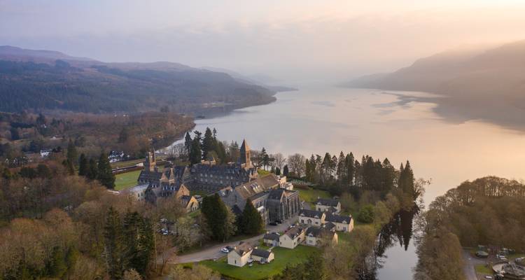 Vue aérienne d'un domaine historique et d'un lac au lever du soleil.