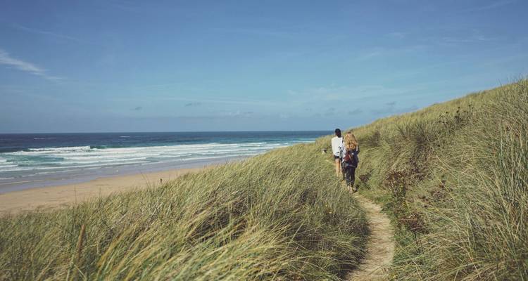 Couple marchant le long d'un sentier sablonneux près de la plage.