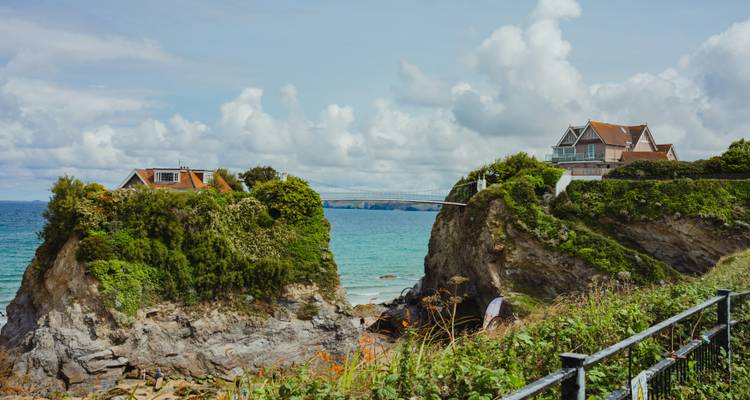 Vue côtière pittoresque avec des maisons au sommet de grandes formations rocheuses.