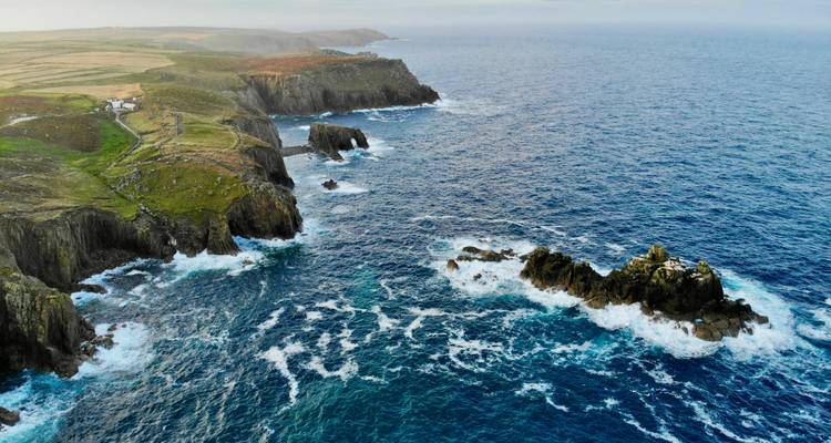 Vue aérienne de falaises escarpées et de côte rocheuse avec océan bleu.