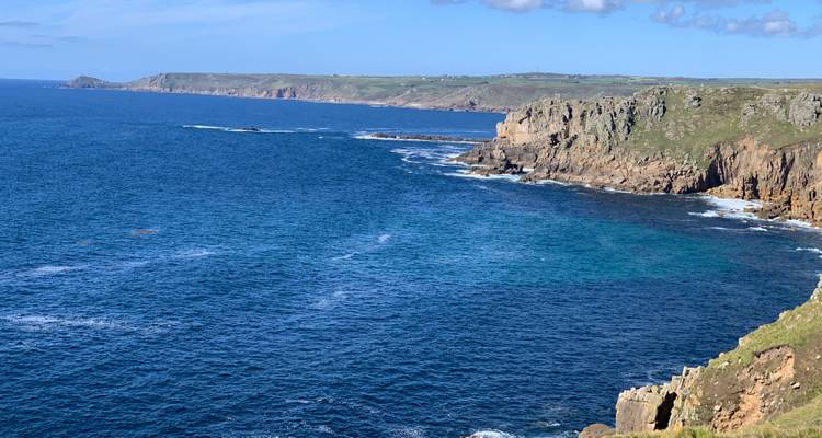 Longue étendue de littoral aux eaux bleues cristallines sous un ciel lumineux.
