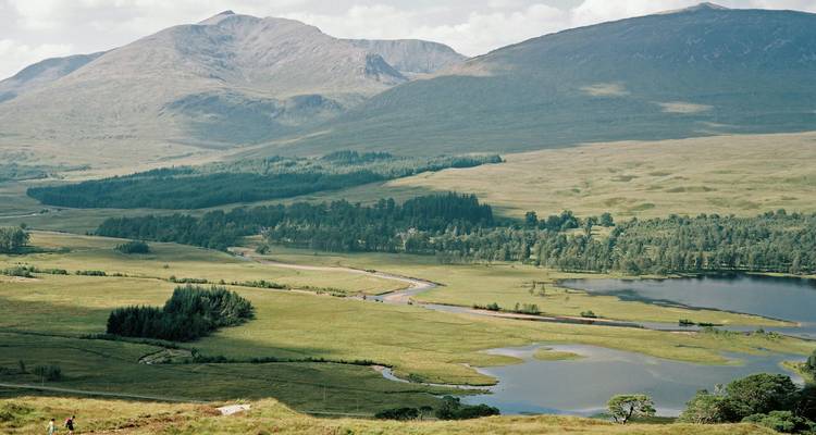 Expansive view of a mountainous landscape with a river and forests.
