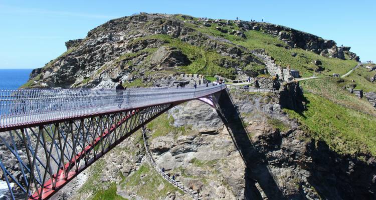 Pont magnifique au-dessus d'une falaise rocheuse avec des touristes qui le traversent à pied.
