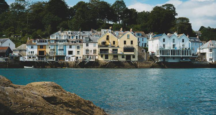 Maisons colorées au bord de l'eau dans un cadre de village pittoresque.