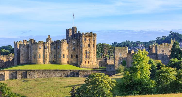 Majestueus middeleeuws kasteel badend in zonlicht omringd door groen.