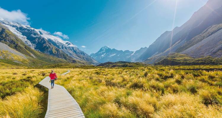 Un randonneur solitaire sur une passerelle avec des montagnes au loin.