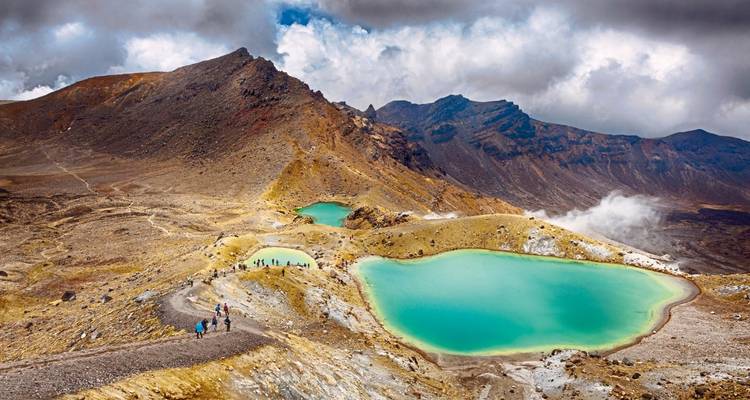 Lacs bleus entourés d'un terrain accidenté et de nuages lointains.
