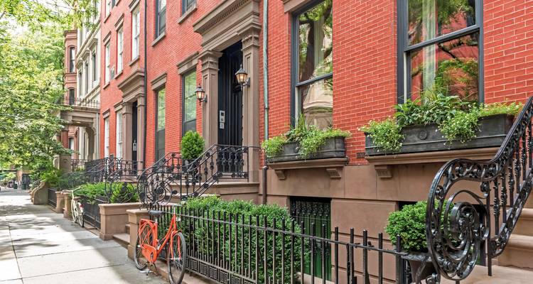 Charmante Reihe traditioneller Brownstone-Häuser mit einem roten Fahrrad in New York City.