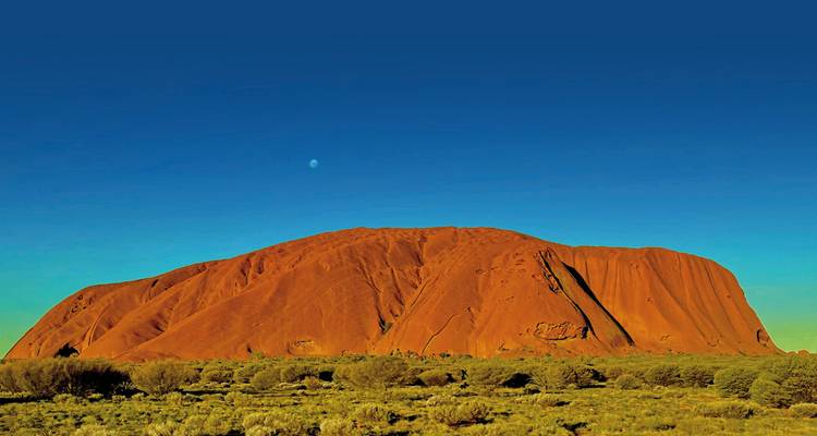 Der rote Sandstein-Monolith von Uluru unter einem klaren Himmel.
