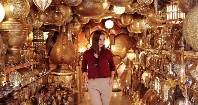 Mujer rodeada de lámparas ornamentadas en una tienda marroquí.